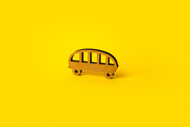 Wooden toy bus over yellow background, public transport bus