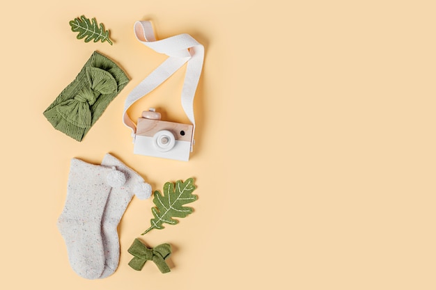 Foto macchina fotografica giocattolo in legno, calzini per bambini e foglie autunnali. set di accessori per bambini alla moda per l'autunno. disposizione piatta, vista dall'alto