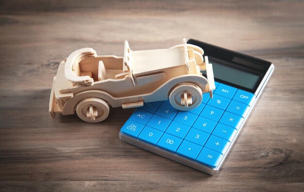 Wooden toy car and calculator on the wooden background