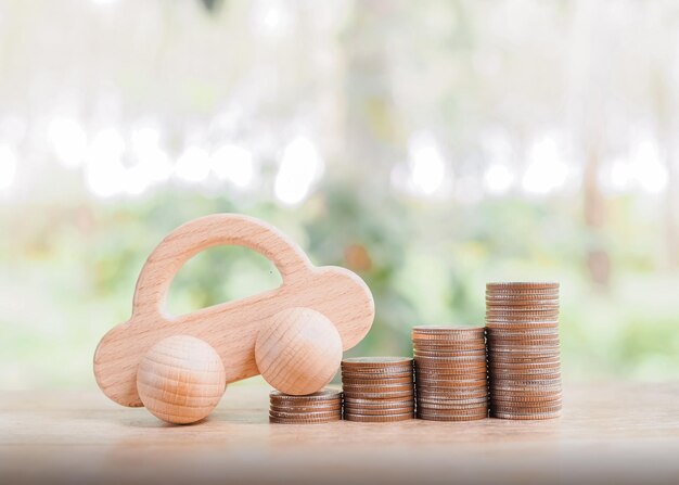 Wooden toy car on stack coins saving money for transport and\
manage for success business concept