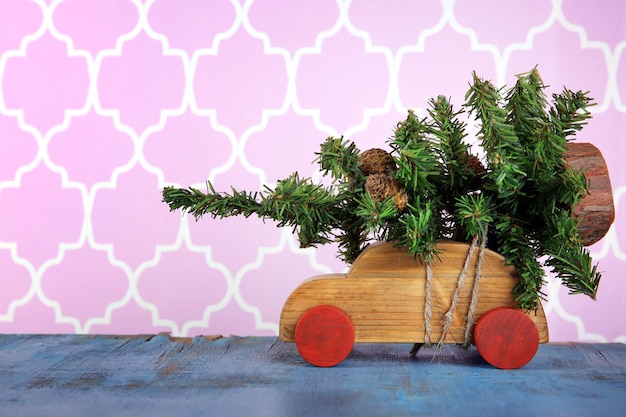 Photo wooden toy car with christmas tree on a table over pattern background