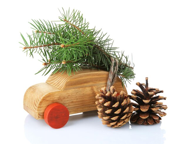 Wooden toy car with fir sprigs and cones isolated on white