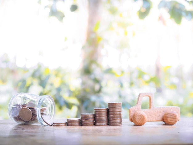 Wooden toy car with stack coins saving money for transport and\
manage for success business concept