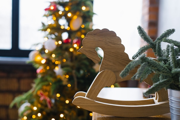 Wooden toy horse and Christmas lights of spruce