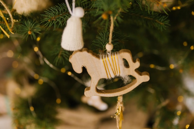 木のおもちゃの馬がモミの木の緑の枝にぶら下がっています。休日の装飾。手作りのおもちゃ。クリスマスと新年。