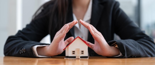 Foto casa giocattolo in legno protetta dalle mani rapporto banner concetto assicurazione casa