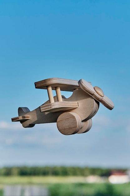 Foto aereo leggero giocattolo in legno biplano che vola nel cielo sopra la campagna aviazione dei cartoni animati