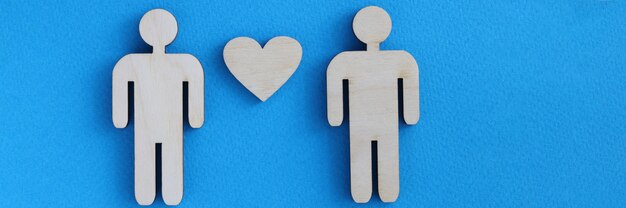 Wooden toy men and heart lying on blue background