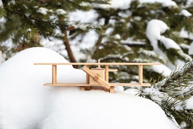Деревянная игрушечная модель самолета в снегу, на фоне зимнего леса. Концепция путешествия, туризм. Красивый зимний фон или открытка. Мечта о путешествии.