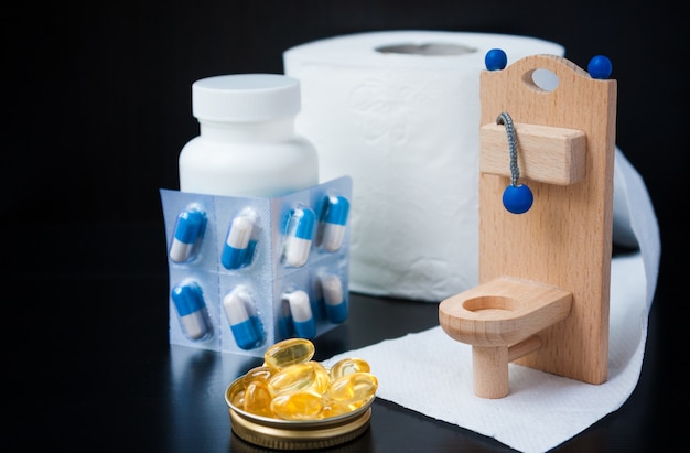 Wooden toy toilet, pills and alarm clock on black