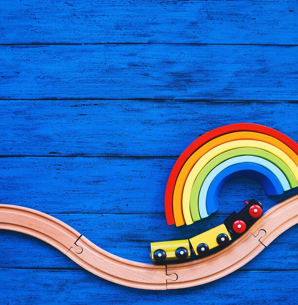 Wooden toy train and railway for preschool child wood rainbow on blue table Colorful waldorf or montessori school background Kids dream travel concept Educational toys for kindergarten children