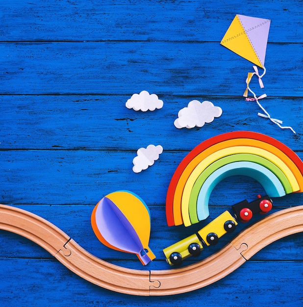 Foto treno giocattolo in legno ferrovia per bambini in età prescolare legno arcobaleno mestieri di carta sul tavolo blu waldorf o sfondo scuola montessori i bambini sognano il concetto di viaggio giocattoli educativi per i bambini della scuola materna