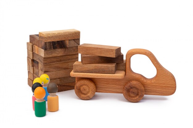 wooden toy of the truck brought the building material in the form of logs to the construction site.