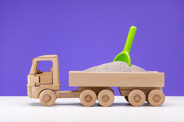 Wooden toy truck miniature filled with sand in it a green duck Fun for boys closeup lilac back