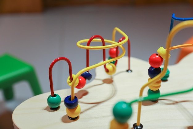 A wooden toy with colorful beads and a red and yellow ball.