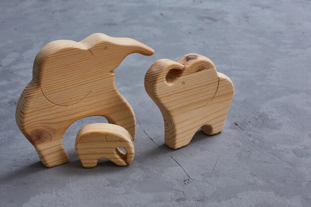 Giocattoli di legno. una famiglia di 3 elefanti scolpiti in un puzzle su un tavolo di cemento grigio