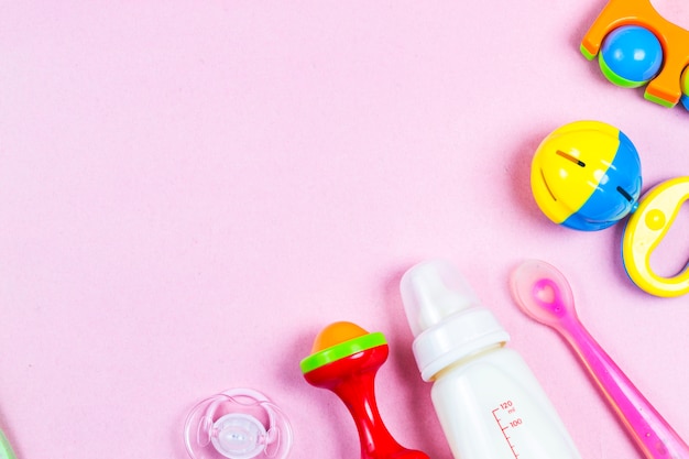 Wooden toys, pacifier and bottle on Pink background