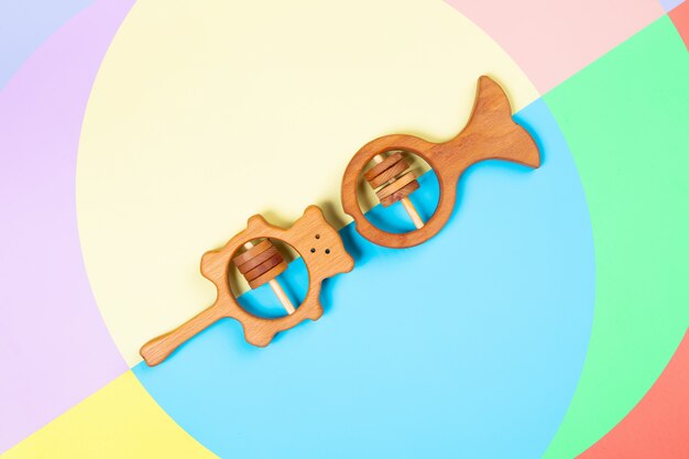  wooden toys, rattles in the form of a fish, bear on pink, blue and yellow isolated background.  