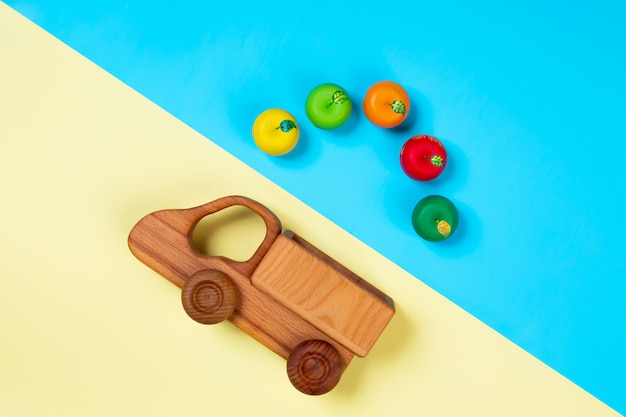 wooden toys trucks with apples on an isolated multicolored vibrant geometric background. 