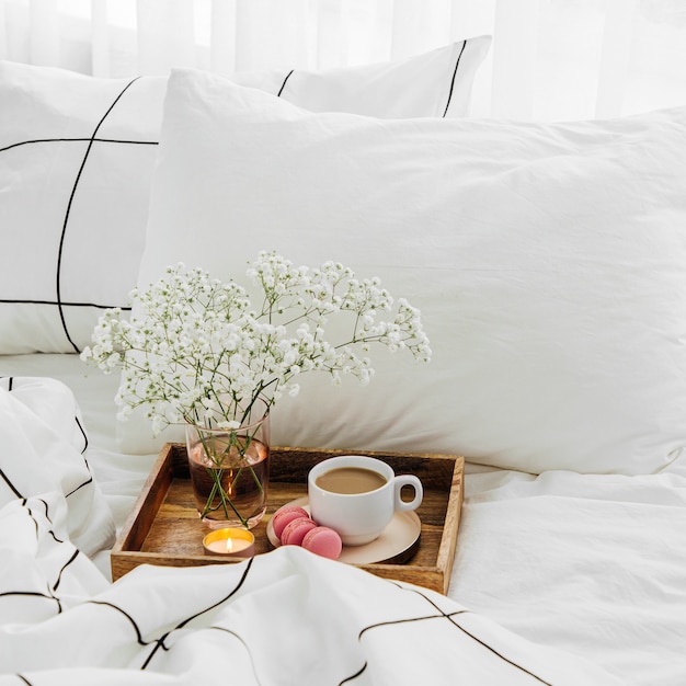 Wooden tray of coffee and candles on bed. Breakfast in bed. Hygge concept.