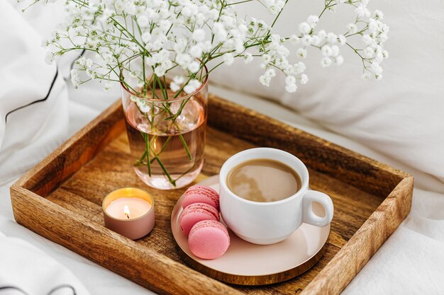 Wooden tray of coffee and candles on bed. Breakfast in bed. Hygge concept.