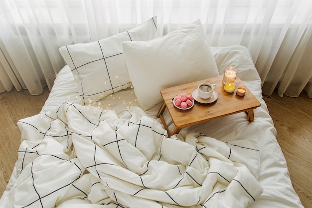 Wooden tray of coffee and candles on bed. Breakfast in bed. Hygge concept.