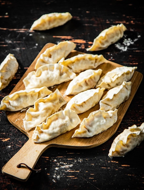 A wooden tray of dumplings with a wooden handle on a wooden surface.