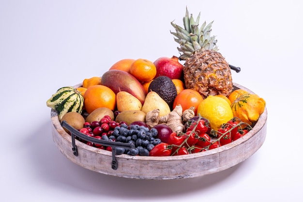 Vassoio in legno di frutta e verdura fresca isolato su uno sfondo bianco girato in uno studio