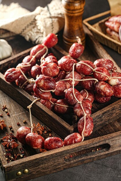 A wooden tray of sausages with garlic and garlic on the side.