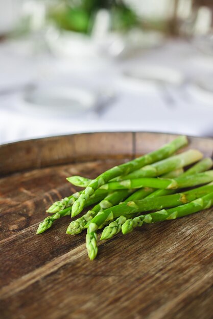 A wooden tray with asparagus on it and a white tablecloth on the side.