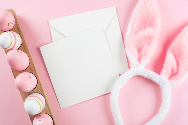 Wooden tray with easter eggs fluffy bunny ears and white empty card for congratulations