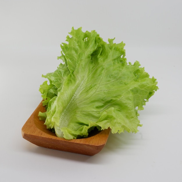 Photo a wooden tray with lettuce on it and a white background.