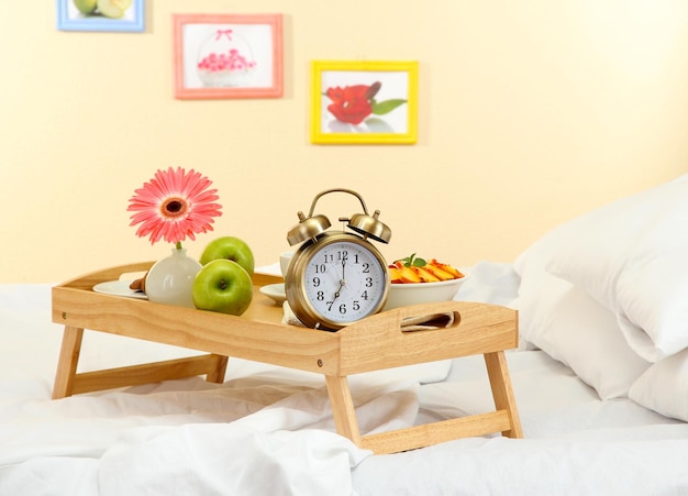 Wooden tray with light breakfast on bed