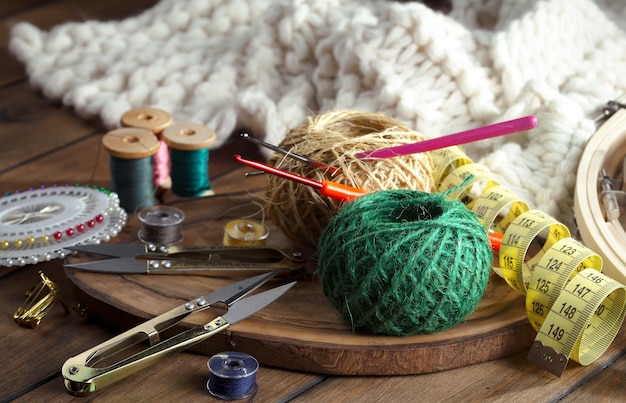 A wooden tray with sewing supplies including a ball of yarn, a needle, a needle, a needle, a needle, a needle, a needle, and a yarn.