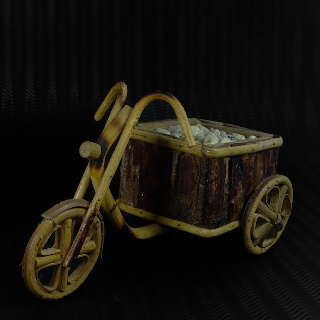 Photo a wooden tricycle with a basket of rocks on it.