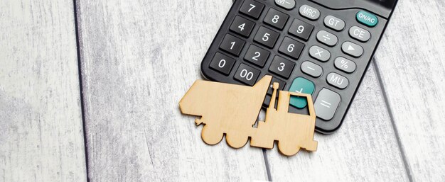 Wooden truck model on calculator on white background