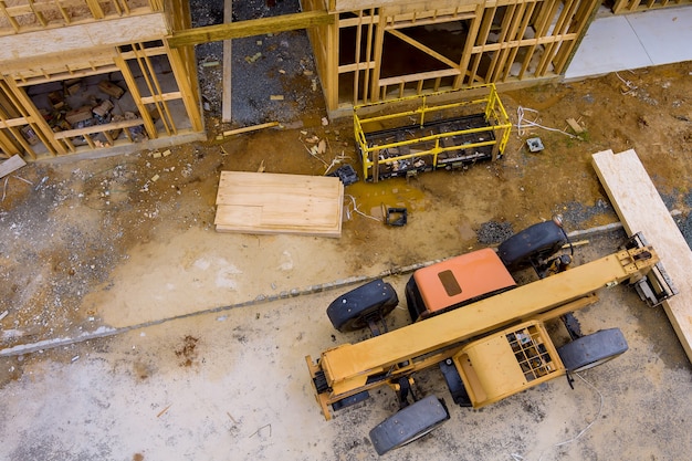 Photo a wooden truss being lifted by a boom truck forklift in the building materials a stack of boards wood frame of a new home