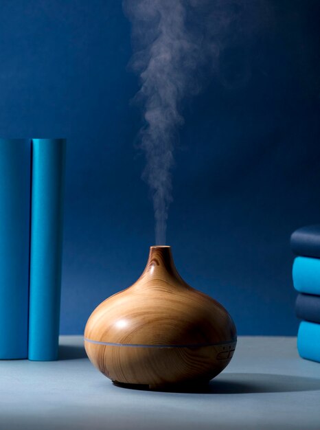 wooden vaporizer with vapor of natural oils, with different ranges of blue, on the gray table in the
