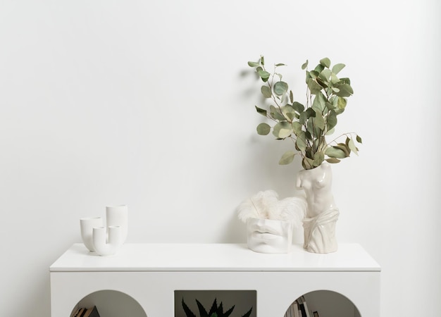 Cornice verticale in legno con vaso bianco di fiori di gipsofila su muro bianco
