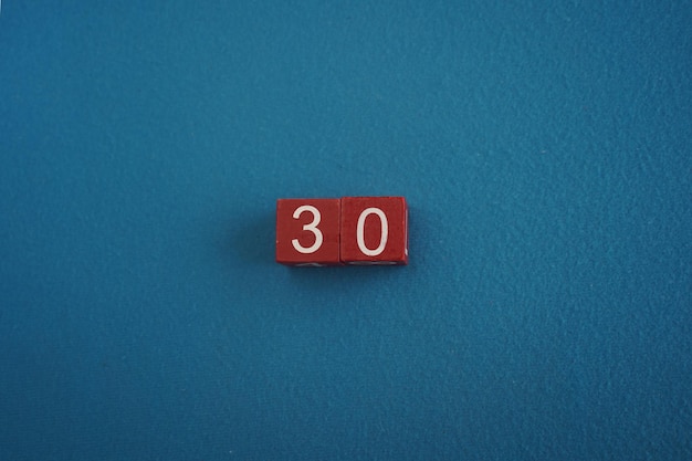 Wooden viva magenta cubes with number 30 on blue background closeup top view concept of date or time white numbers 30 on red cubes velvet background copy space for text or event educational cubes