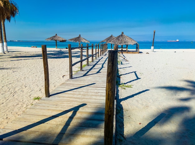 Wooden walkway on the beach with umbrellas in the background