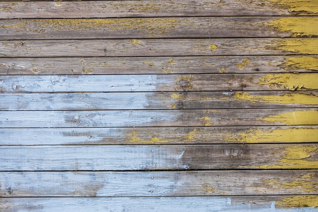 Wooden wall with horizontal planks with old blue and yellow paint