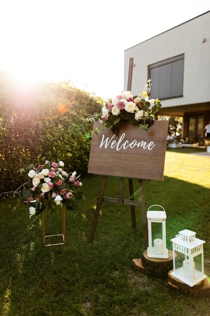 wooden welcome board at outdoor wedding venue.