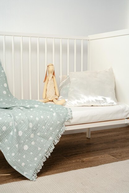 Photo wooden white baby crib and toy rabbit close up