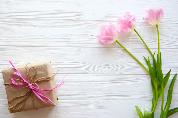 Wooden white background,present and pink tulips.  March 8, Mother's Day.