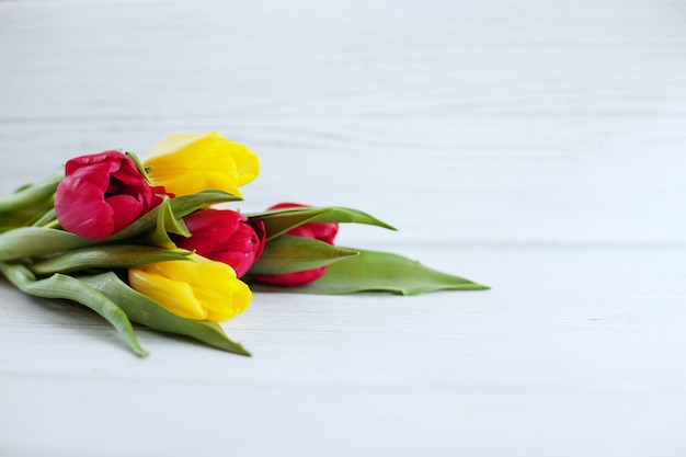 Wooden white background and yellow and red flowers. 