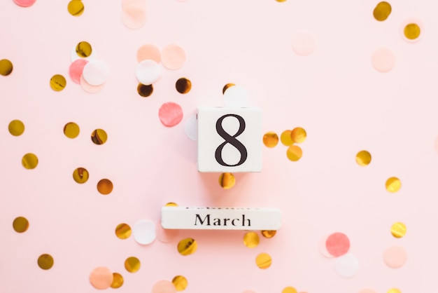 Деревянный белый календарь с датой 8 марта на розовом фоне с конфетти. концепция же праздника, красоты, любви и феминизма. copyspace, шаблон