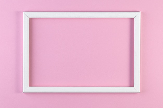 Wooden white frame on pink pastel color background.