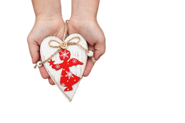 Wooden white heart with a red angel in childrens hands