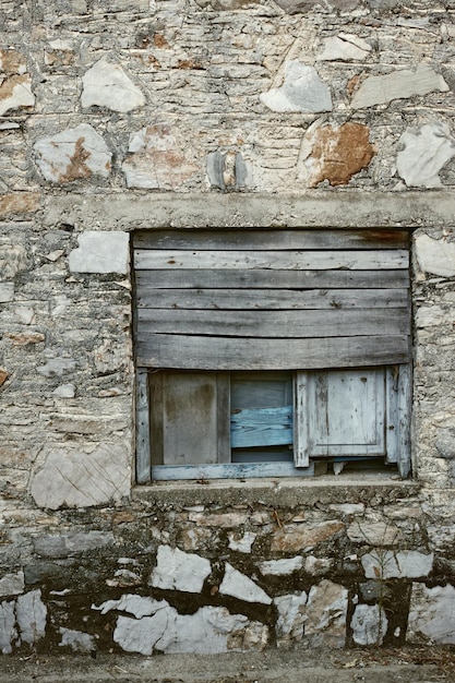 Wooden window boarded on an old rough stone wall farmhouse or\
ancient house vintage rustic old fashioned frame and shutters on\
historic village building antique architecture structure\
background